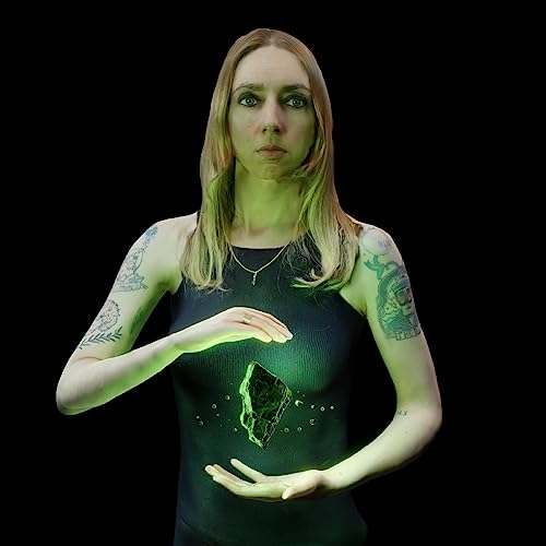 Woman with tattoos holding a glowing, dark stone in her hands.