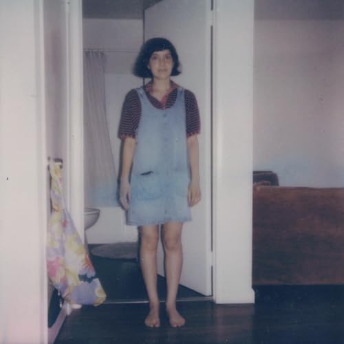 Woman in denim dress standing in a room, vintage photograph.