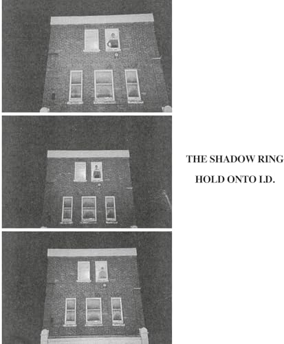 Black and white grainy image of a brick building with lit windows.