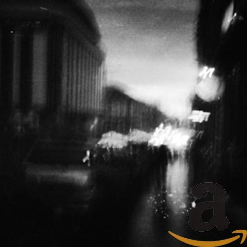 Blurry black and white city street scene with bright lights, Amazon logo.