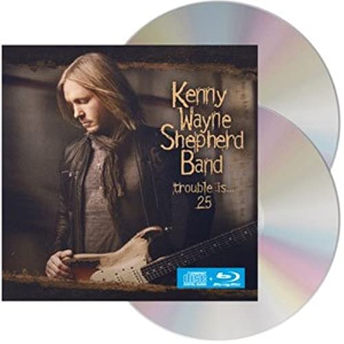 Kenny Wayne Shepherd holding a guitar on the cover of the Trouble Is... 25 CD.