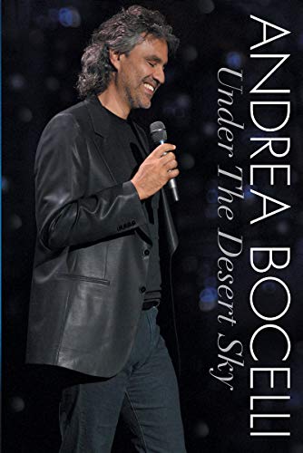 Andrea Bocelli smiling while holding a microphone on stage against a dark background.