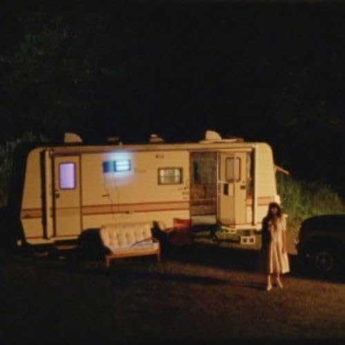 Vintage RV parked at night with a woman standing nearby.