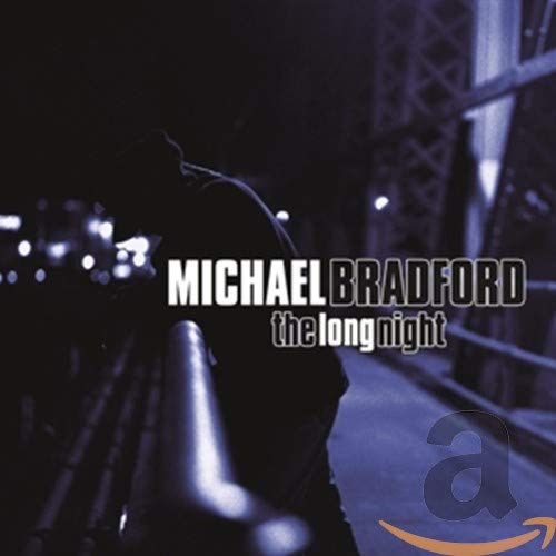 CD cover: man with hood looking at blurred city lights at night.