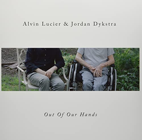 Two men seated outdoors, one in a wheelchair, against a green background.