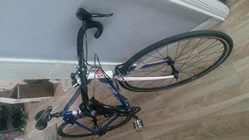Blue and white road bike leaning against a wall indoors.