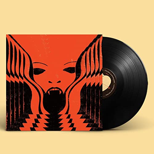 Vinyl record beside a square album cover featuring a stylized orange and black face.