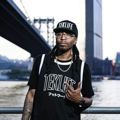 DJ Spinn portrait with dreadlocks, wearing a cap and black jersey.