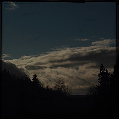 Dark, cloudy sky over silhouetted trees; album cover art.