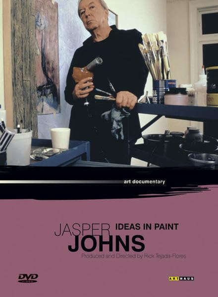 Jasper Johns, an older man, stands in his art studio with painting supplies.