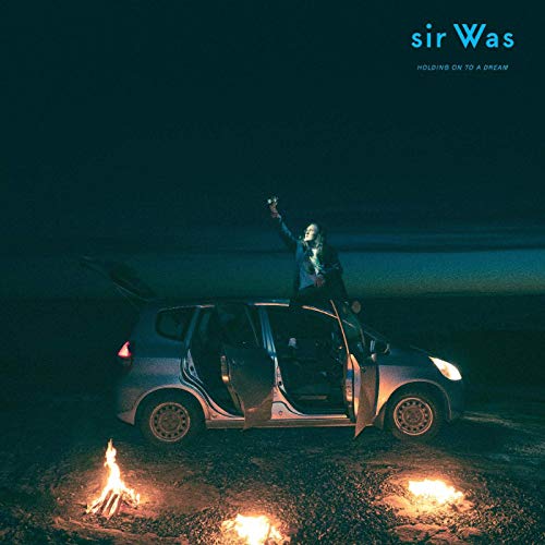 Album cover: person on car with campfire, dark blue sky.