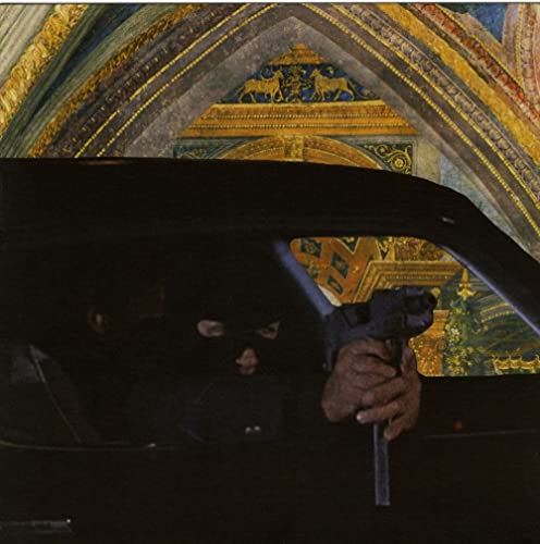 Person holding a gun from inside a dark car, ornate background.