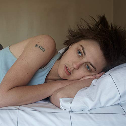 Young woman with short hair lying on a white pillow.