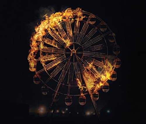Burning Ferris wheel against a dark, blurred city background.