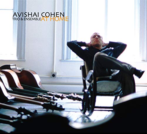 Avishai Cohen album cover: man relaxing in a chair with guitars.
