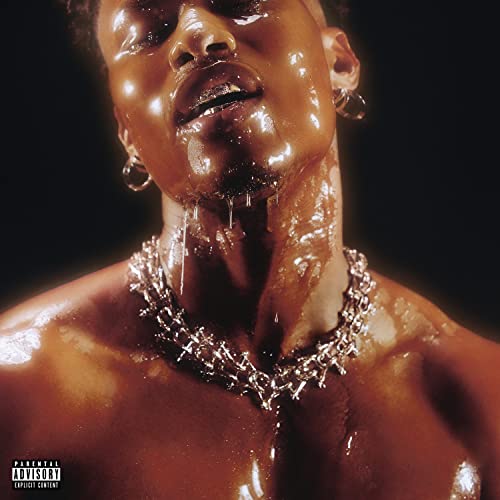 Close-up of Lucky Daye covered in a glossy, dripping substance, wearing jewelry.