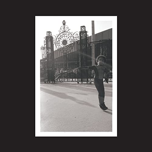 Black and white album cover featuring a person before ornate iron gates.