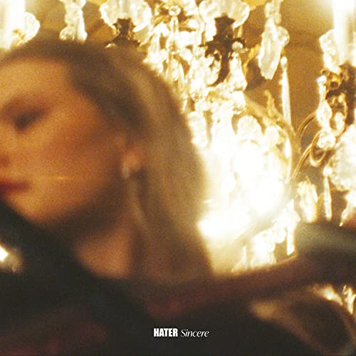 BlurLofi, blurred close-up of a person's face against a glowing crystal chandelier background.