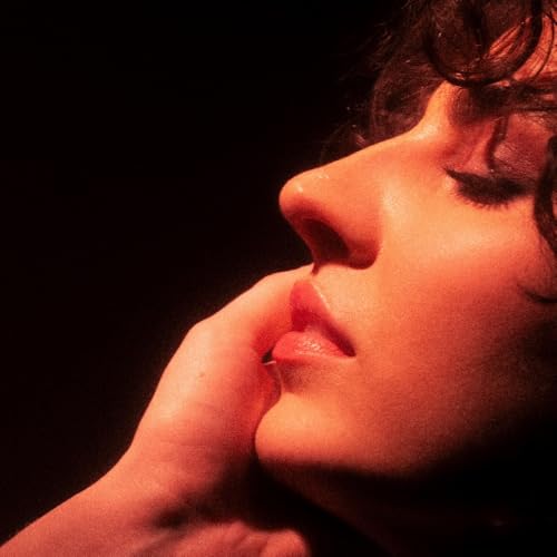 Close-up of a woman’s face in red lighting, partially obscured by a hand.