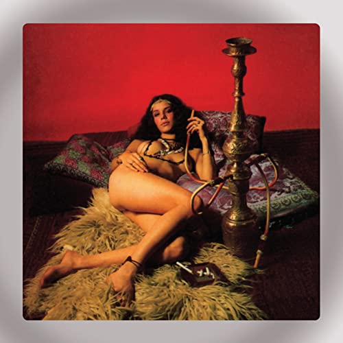 Woman in gold jewelry reclining on cushions next to a tall hookah.