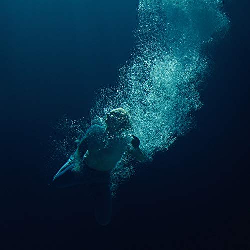 Person submerged underwater, bubbles rising, dark blue tones.
