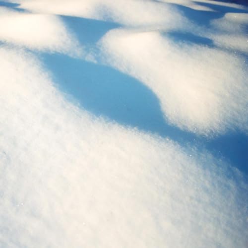 Snowy landscape with blue sky visible through cloud-like drifts.