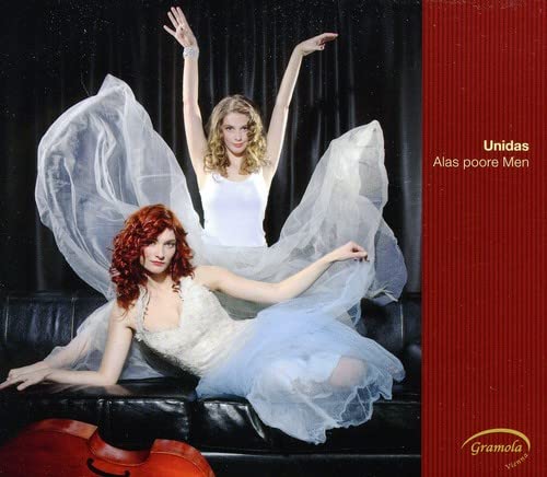 Two women in flowing dresses pose on a black couch, album cover.