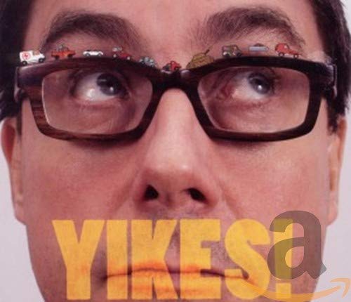 Close-up of a man with toy cars balanced on his glasses, "YIKES" text.