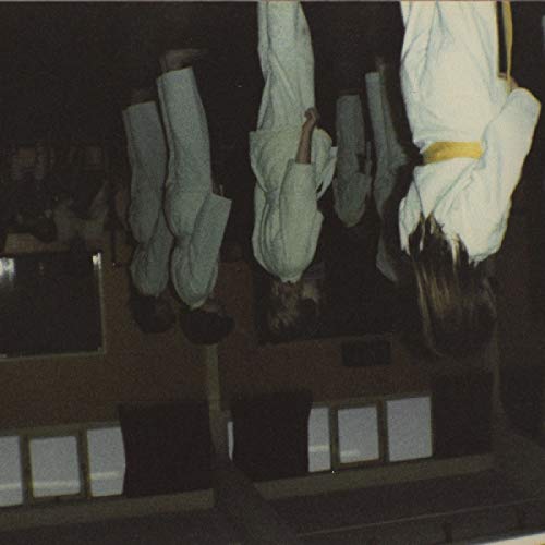 Hanging figures in white suits against a dark, blurred background.