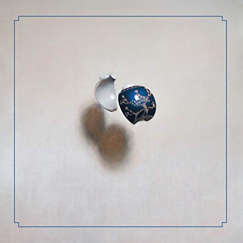 Dark blue egg with gold branches, partially cracked, on a light surface.
