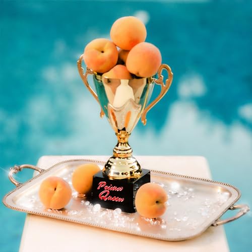 Gold trophy overflowing with peaches on a silver serving tray.