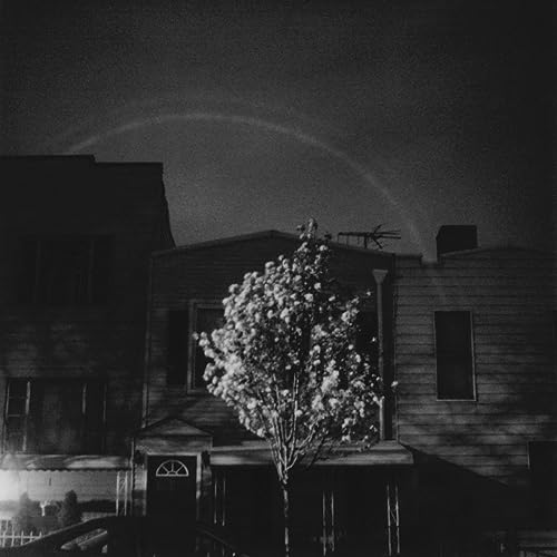 Black and white photo of a house, tree, and faint circular rainbow.