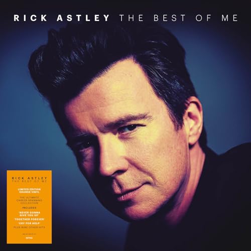 Close-up portrait of Rick Astley against a blue background with an orange sticker.