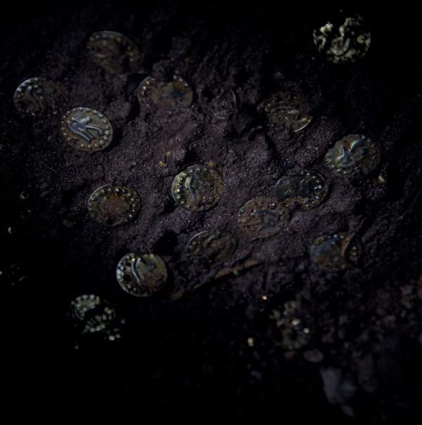 Dark, textured surface with numerous circular objects resembling coins.