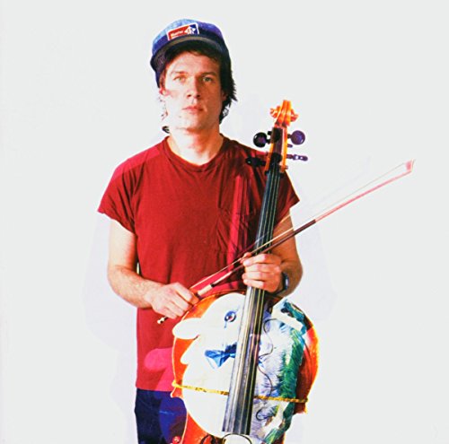 Arthur Russell with cello, wearing a cap and red shirt.