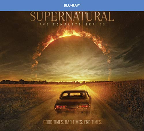 A car drives down a dirt road toward a fiery arch in the sky.