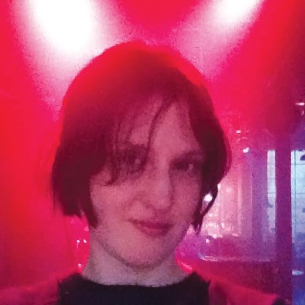 Portrait of a person with short dark hair, bathed in red light.