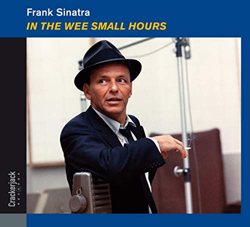 Frank Sinatra in a hat and suit, singing into a vintage microphone.