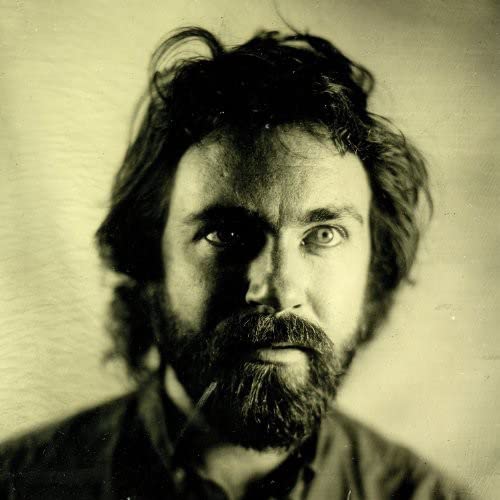 Close-up portrait of a man with dark hair and a full beard.