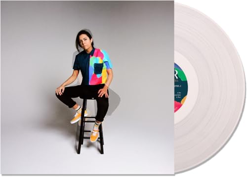 Woman on stool next to a white vinyl record.