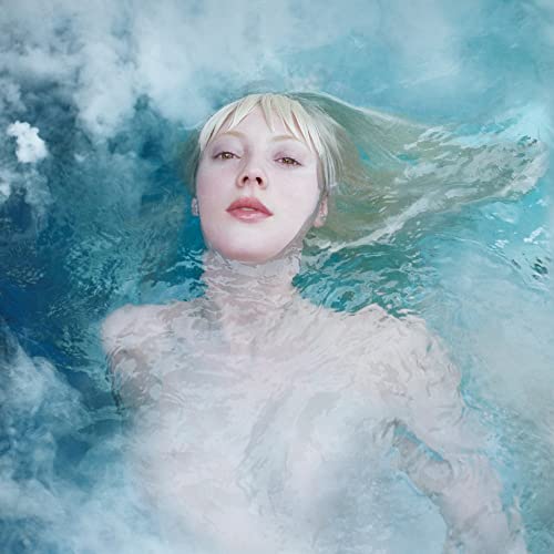 Woman with wet blonde hair floating in blue, cloudy water.