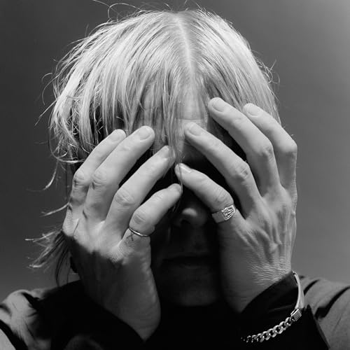 Black and white portrait of a person with hands covering their face.