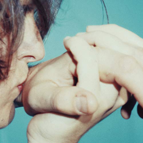 Close-up of hands intertwined with a partial face on teal background.
