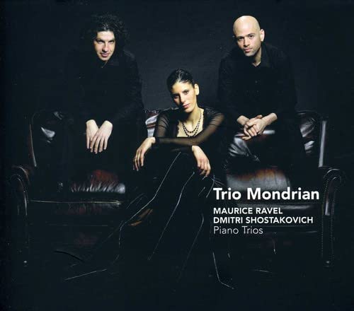 Trio Mondrian members seated on a brown leather couch, dark background.