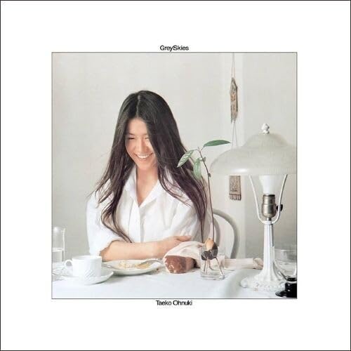 Album cover: smiling woman with long hair, lamp, and table setting.