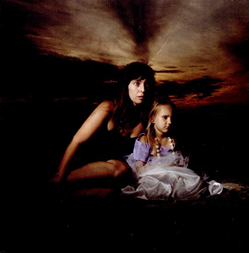 Two women sit against a dark, cloudy sky in a vintage photograph.