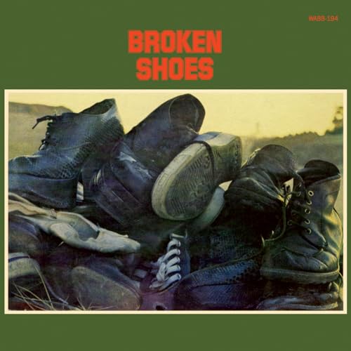 Vinyl record cover with a photo of worn, broken shoes in a field.