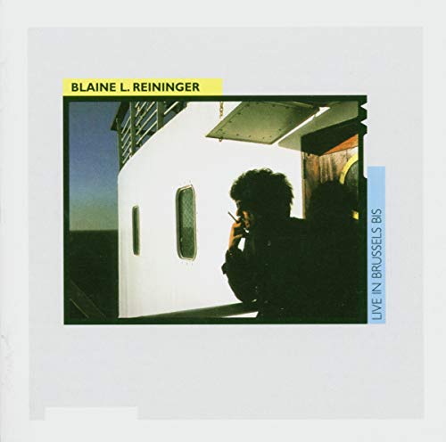 Album cover featuring a man with curly hair in front of a building.