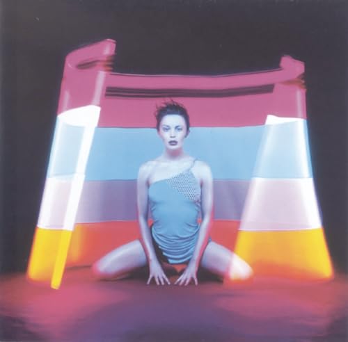 Kylie Minogue kneels before a colorful, inflatable castle-like structure.