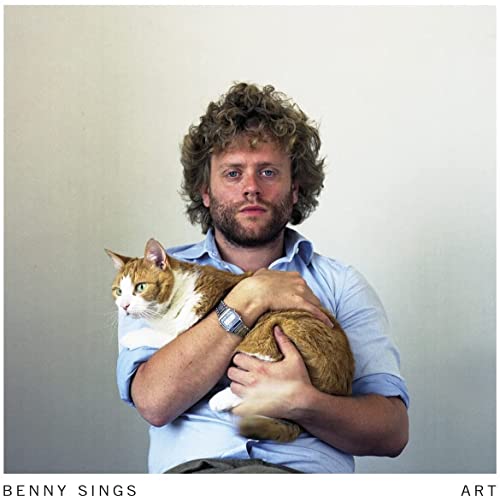Man with curly hair holding a ginger cat, album cover.